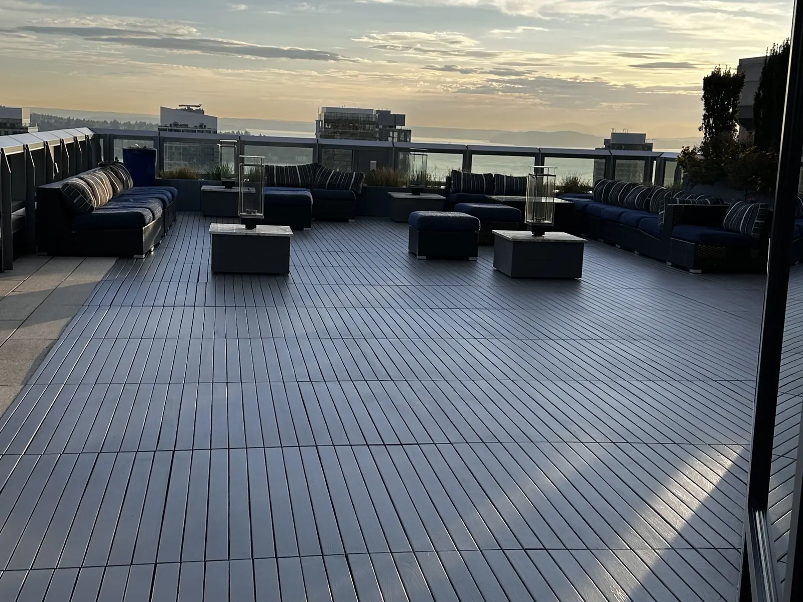 Rooftop terrace with dark decking, outdoor seating and railings at sunset
