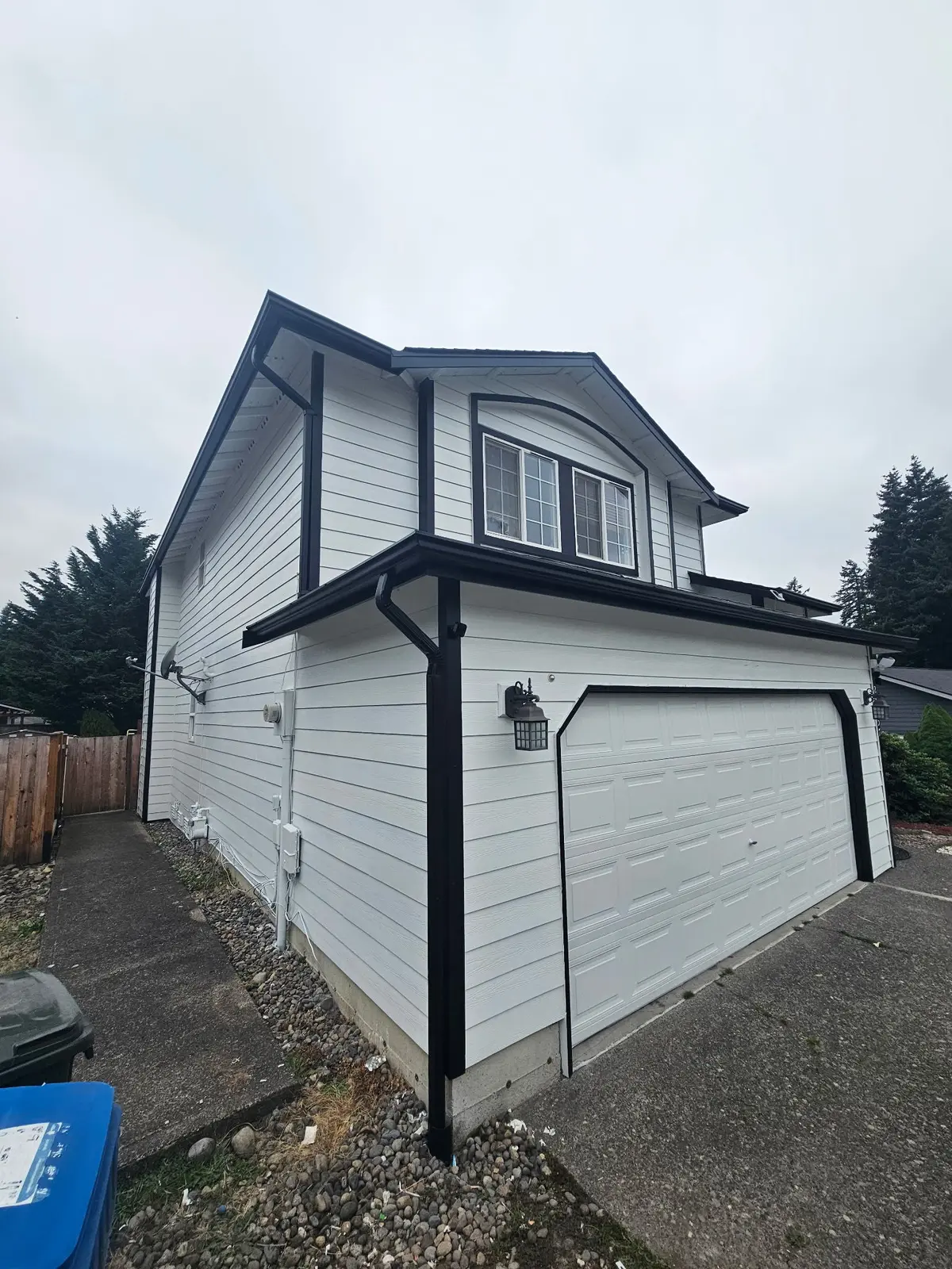 House exterior with white siding, dark trim and a white garage door